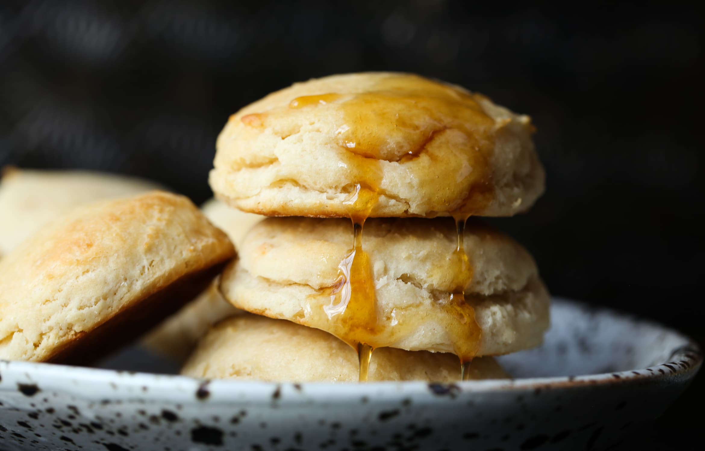 Yeast Biscuits stacked on a plate with honey dripping down the top.