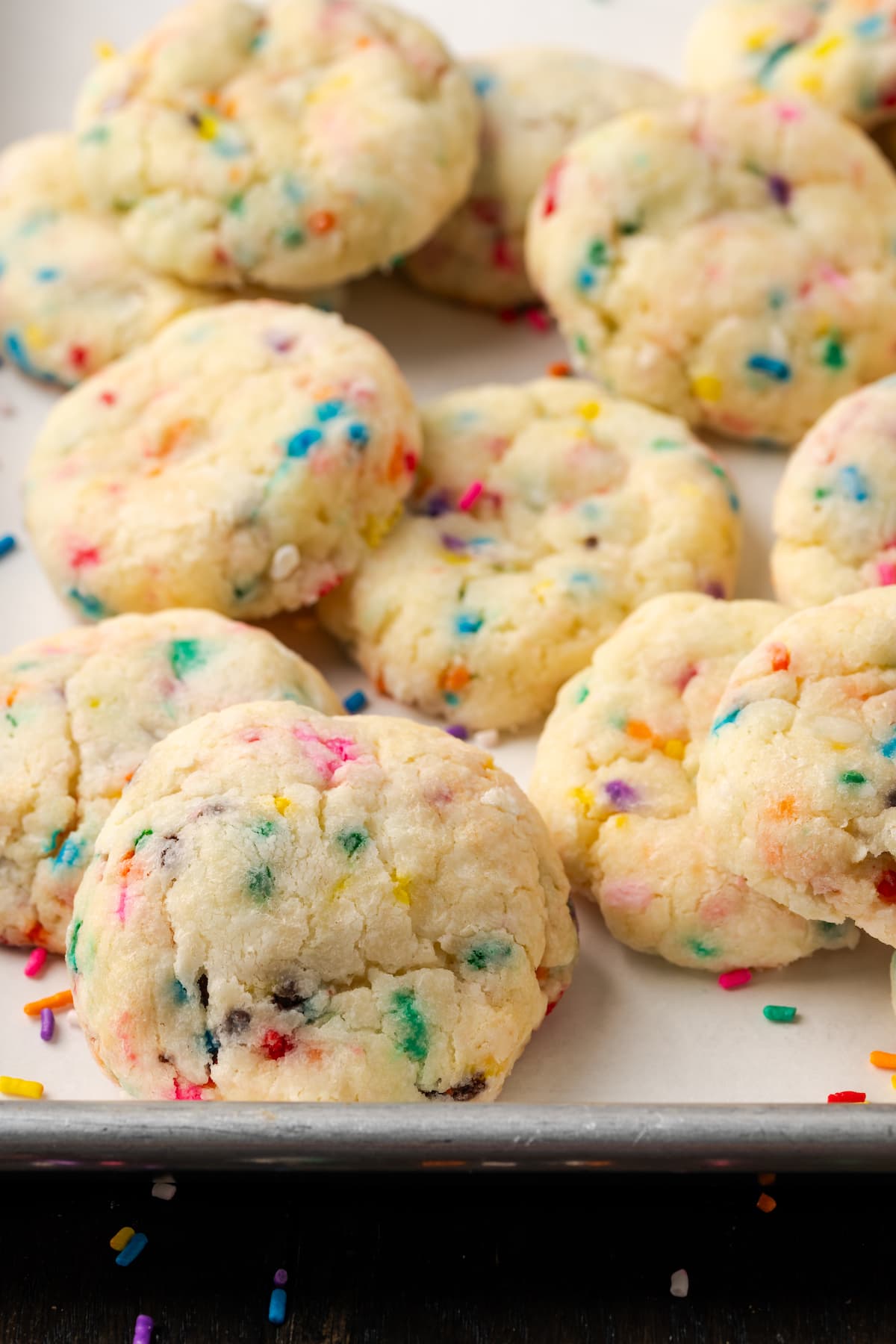 Close up of assorted funfetti cookies on a parchment-lined baking sheet.