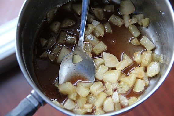 Top view of peeled, diced apples cooking with cinnamon in a saucepan