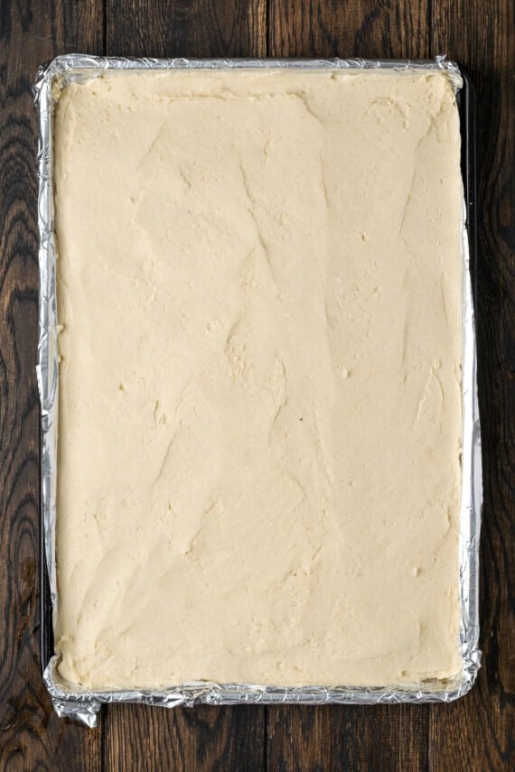 Sugar cookie dough pressed into a lined baking pan.
