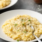 Pastina served on a white plate topped with black pepper and parmesan.