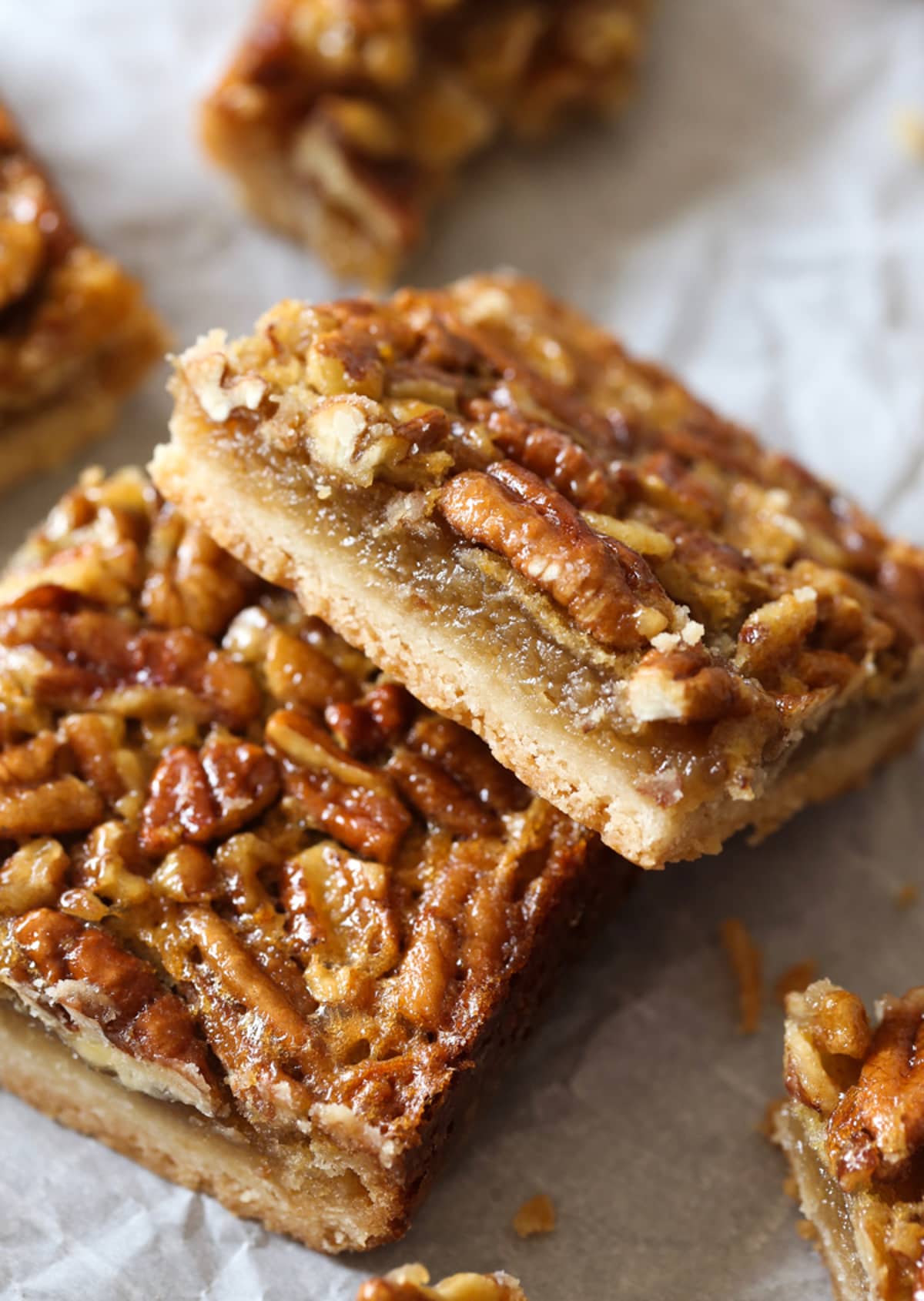 Cut pecan pie bars on a piece of parchment paper tilted to the side showing the inside layers of the bar
