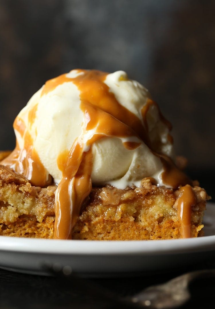 A slice of Pumpkin Dump Cake with a scoop of ice cream and caramel sauce.
