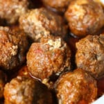 Slow cooker ricotta stuffed meatballs served over pasta on a plate set on top of a striped cloth.