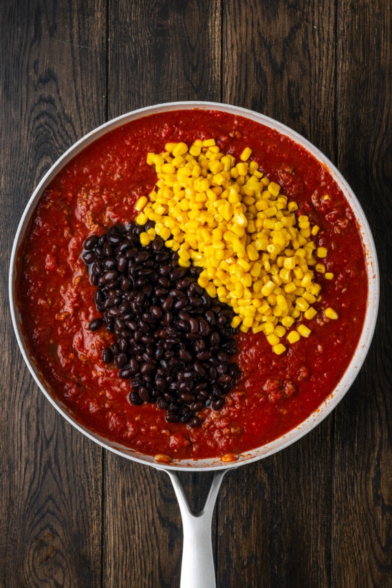 Corn and black beans added to a pan of taco meat mixture.